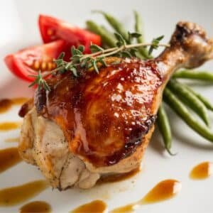 Honey-Glazed Roasted Chicken Quarters Recipe - Tender, oven-baked chicken quarters coated in a rich honey glaze, garnished with fresh thyme, and served with crisp green beans and juicy cherry tomatoes. A flavorful and easy chicken dish perfect for any meal.