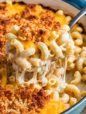Tini's Mac and Cheese Recipe featuring creamy, cheesy macaroni with a golden, crispy breadcrumb topping, served in a light blue casserole dish. A rich and comforting homemade baked mac and cheese perfect for any occasion.
