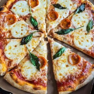 Homemade Margarita Pizza with melted mozzarella, basil leaves, and a few pepperoni slices in a cardboard box.