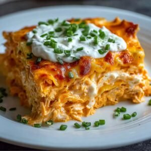 Easy Buffalo Chicken Lasagna slice on a white plate, showing layers of creamy shredded chicken in orange buffalo sauce, melted cheese, and golden-browned top, sprinkled with fresh parsley.