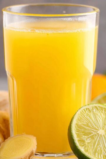 Homemade Ginger Shot Recipe | 5 Ingredients, 5 Minutes 30 ginger Shot recipe Close-up of a refreshing glass of ginger juice, served with a slice of lime and ginger roots around.