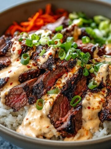 Homemade Korean BBQ Steak Bowls with sliced grilled steak, rice, spicy mayo, scallions, carrots, and greens.