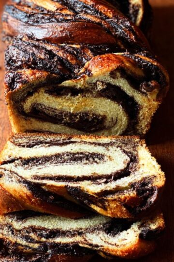 Best Babka Recipe | Chocolate Orange Swirl Bread 22 Babka Recipe A rustic chocolate babka loaf sliced thick, showing dramatic dark chocolate swirls inside soft golden bread, placed on a wooden cutting board, natural window light, top-down food photography, artisanal bakery style, high detail, warm tones