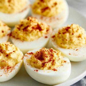 Deviled Eggs Recipe - Perfect in 35 Minutes or Less! 19 Deviled Eggs Recipe A white plate arranged with freshly made deviled eggs, each topped with a sprinkle of paprika. The deviled eggs are neatly placed in a row, ready to be served.