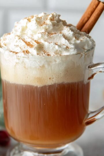 Hot Buttered Rum Recipe | Easy 10-Minute Winter Cocktail 27 Hot Buttered Rum Glass mug of hot buttered rum topped with whipped cream and cinnamon sticks, styled with red berries and warm spices on a gray surface.