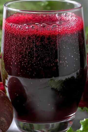 How to Make Beetroot Juice at Home - 2 Easy Ways 25 beetroot juice Clear drinking glass of homemade beet juice with visible bubbles, fresh beets and leafy greens placed around for a natural healthy drink presentation.