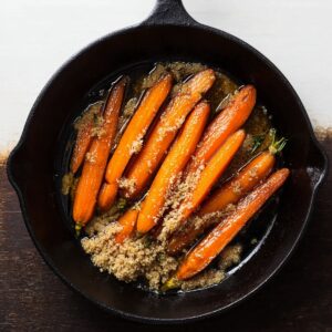 Best 5-Ingredient Brown Sugar Glazed Carrots Recipe 17 A skillet showing raw carrots and a cube of butter placed on top, ready to begin cooking. The butter is melting into the pan, preparing to coat the carrots for caramelization, with the fresh, whole carrots giving an inviting and fresh appearance.