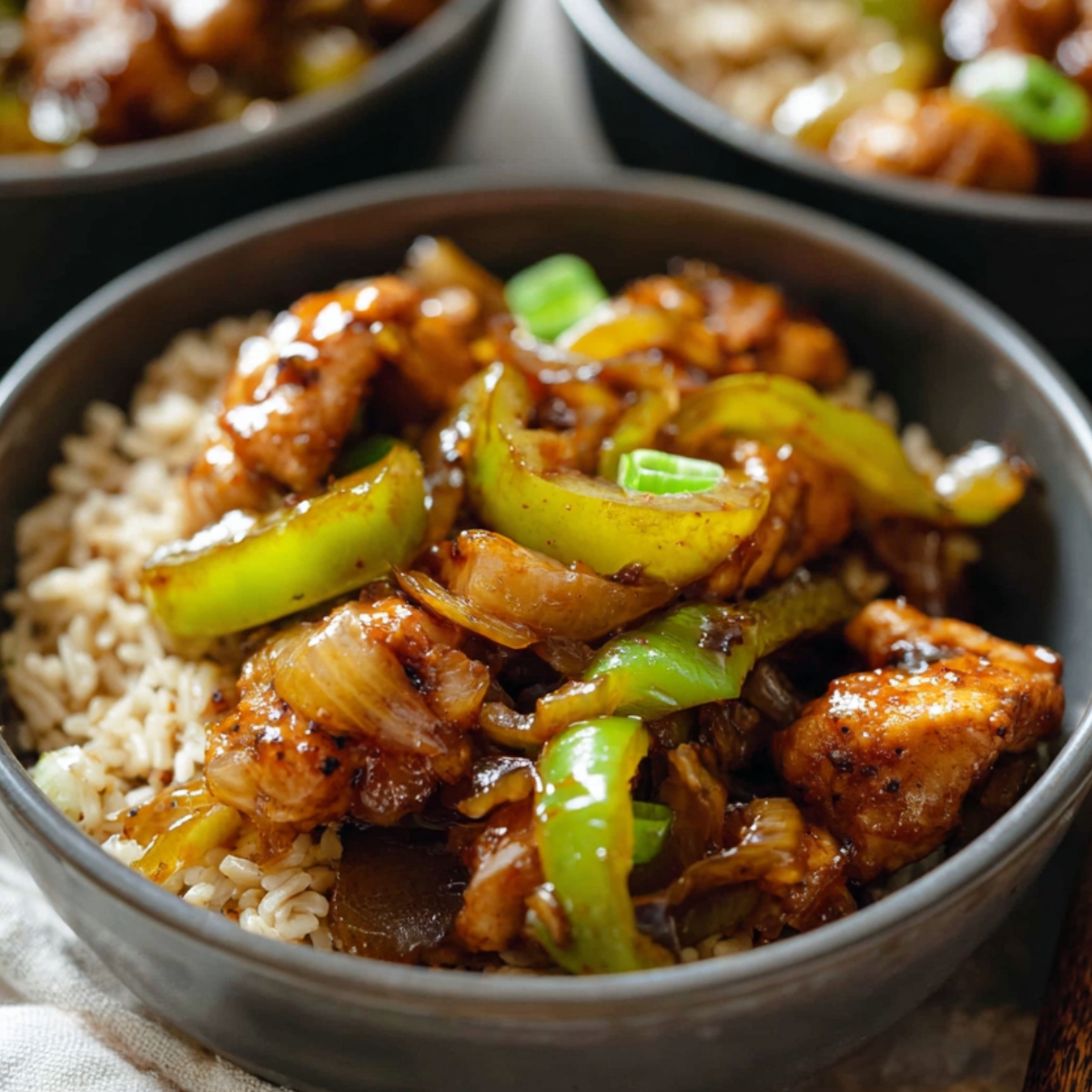 Black Pepper Chicken Recipe Asian black pepper chicken rice bowls garnished with scallions on a wooden table