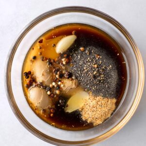 Easy Black Pepper Chicken Recipe 15 Black pepper chicken sauce ingredients in a glass bowl with soy sauce, garlic, ginger, and cracked pepper