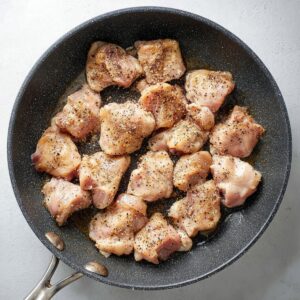 Easy Black Pepper Chicken Recipe 16 Seasoned chicken pieces cooking in a skillet with black pepper and oil