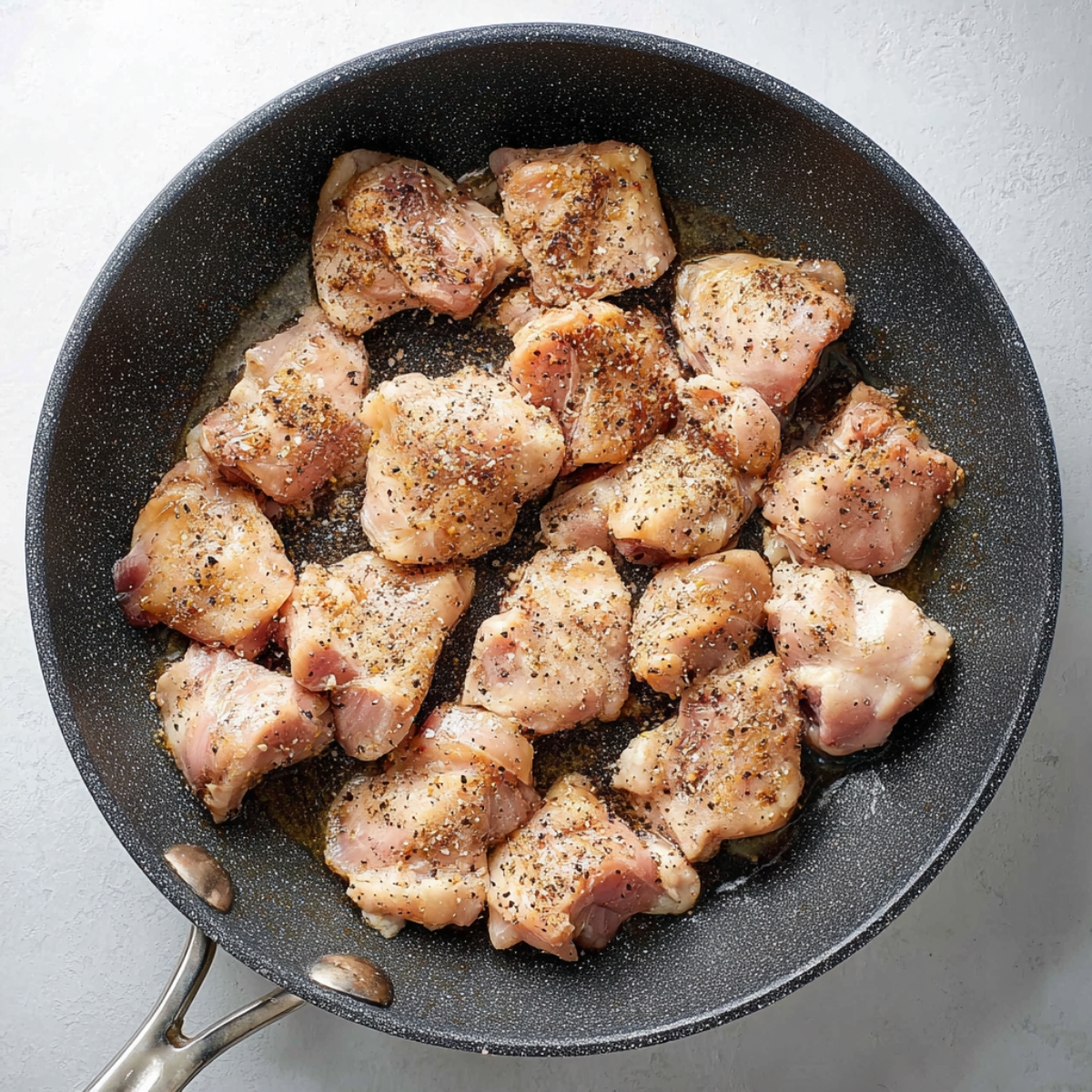 Easy Black Pepper Chicken Recipe 12 Seasoned chicken pieces cooking in a skillet with black pepper and oil