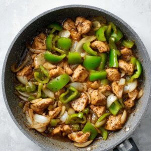 Easy Black Pepper Chicken Recipe 17 Stir-fried black pepper chicken with green bell peppers and onions in a pan