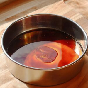Filipino Leche Flan Recipe (Silky & Easy!) - 5 Ingredients 15 Liquid caramel syrup coating the bottom of a round metal baking pan for leche flan.
