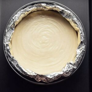 Best Lemon Cheesecake Recipe 17 Overhead image of cheesecake batter in a foil-wrapped springform pan placed inside a roasting pan for a water bath