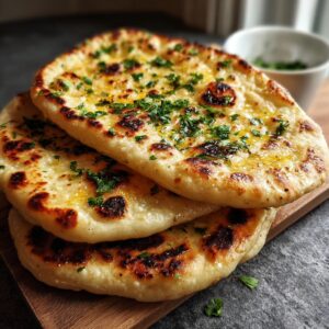 Healthy Naan Bread Recipe 17 Stack of freshly cooked garlic naan brushed with herb butter and garnished with chopped parsley.
