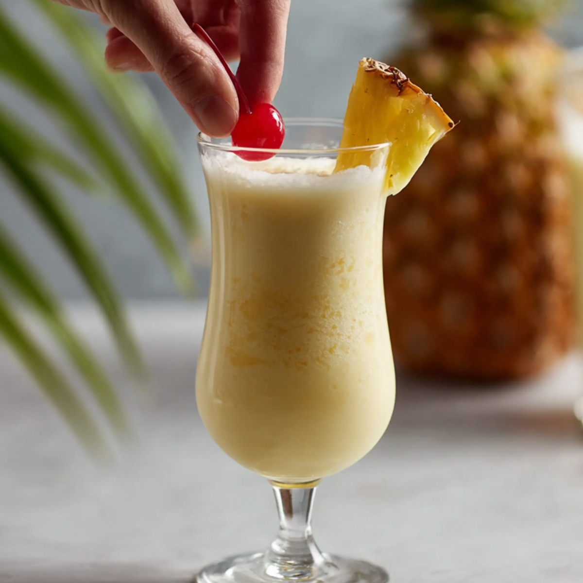 Delicious Piña Colada Recipe 12 The final image shows the drink after it’s been poured into a glass, garnished with a pineapple slice and a cherry. The colorful umbrella adds a festive look, making it ready for serving!