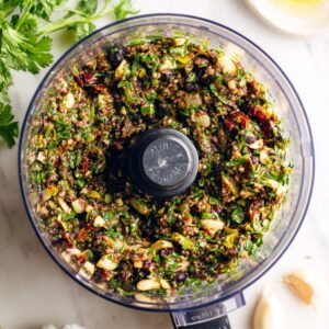 10-Minute Olive Tapenade Recipe | Bold & Easy Appetizer 14 Top-down view of freshly blended olive tapenade inside a food processor, showing a coarse texture with herbs, garlic, and olives.