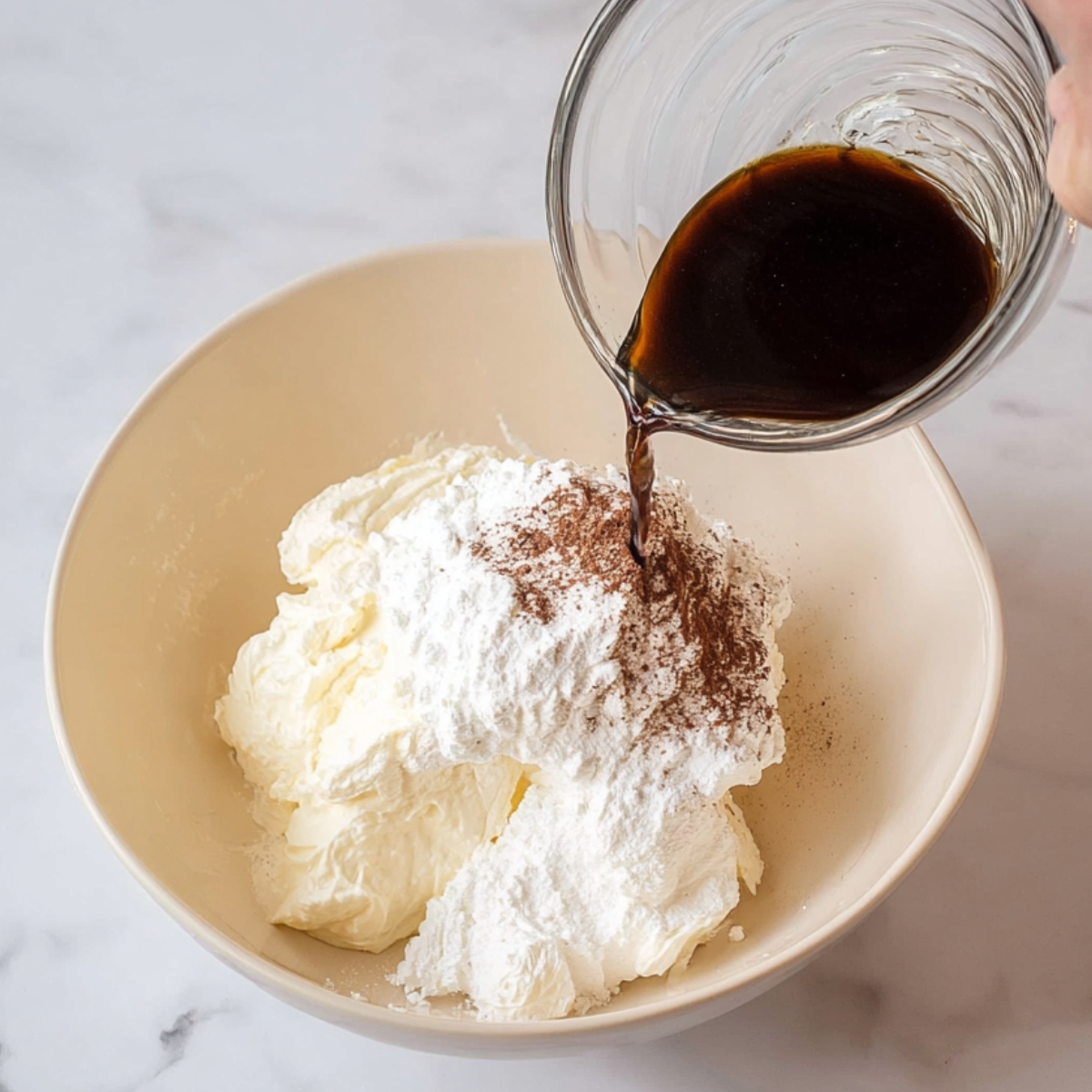 Tiramisu Crepe Cake Recipe | Easy 6-Step Guide 11 A hand pouring espresso coffee over a bowl filled with mascarpone cheese, cream cheese, powdered sugar, and cocoa powder, ready to be mixed into a creamy filling.