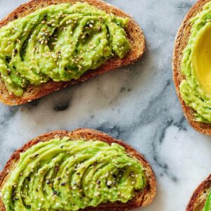 Easy Avocado Toast Recipe | Ready in 5 Minutes 16 “Top-down view of toasted bread slices spread with mashed avocado and sprinkled with seeds on a marble background.”