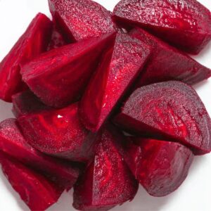 How to Make Beetroot Juice at Home - 2 Easy Ways 14 Top-down view of freshly cooked or raw beet chunks cut into wedges, vibrant red color, glossy texture, arranged closely on a white background.