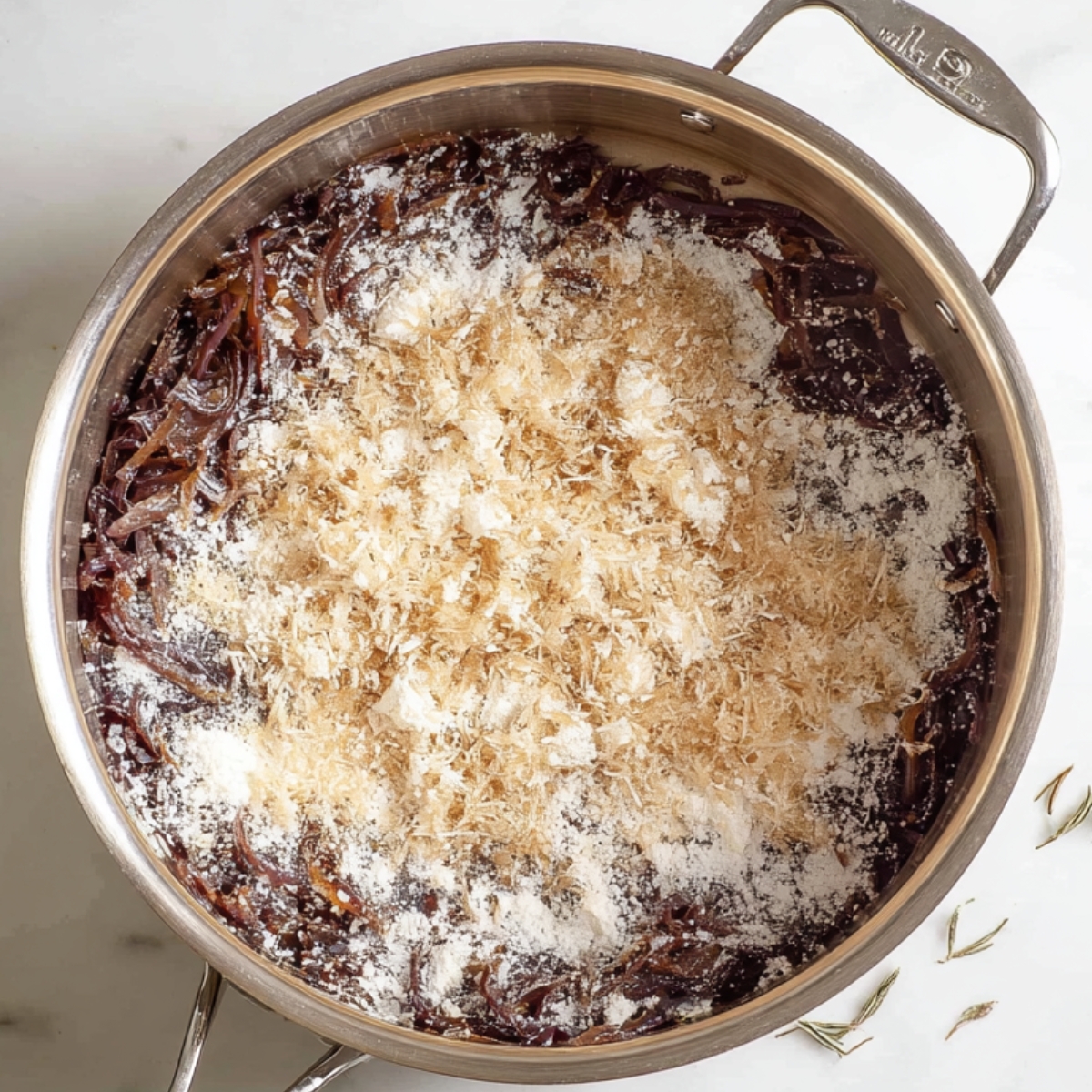 French Onion Soup Recipe - Rich & Easy in 1 Hour 11 Top-down view of caramelized onions in a stainless-steel pot sprinkled with flour during the soup-making process.