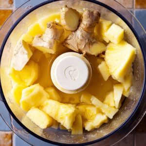 Homemade Ginger Shot Recipe | 5 Ingredients, 5 Minutes 15 Chunks of ginger and pineapple in a food processor, ready to be blended into a fresh juice