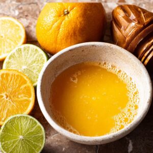 Homemade Ginger Shot Recipe | 5 Ingredients, 5 Minutes 14 Close-up of freshly squeezed ginger juice with lime slices and a citrus juicer beside.