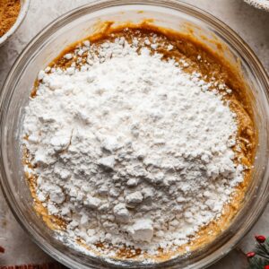 Easy Gingerbread Cake Recipe | Moist & Perfectly Spiced 16 Overhead view of gingerbread cake batter in a glass bowl covered with a thick layer of white flour before mixing.