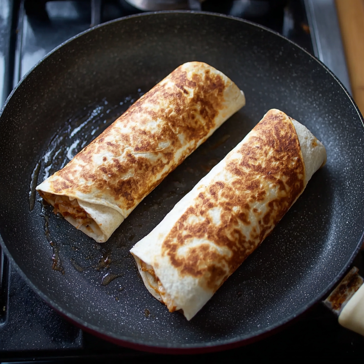30-Minute Grilled Chicken Burrito - Crispy & Cheesy 12 Two chipotle ranch grilled chicken burritos cooking in a non-stick skillet, turning golden brown and crispy on the outside.