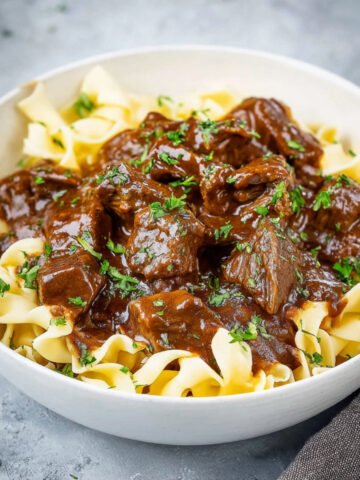 Tender Beef and Noodles covered in thick brown gravy, garnished with parsley