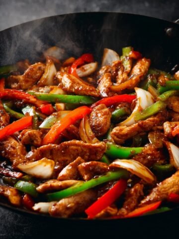 Spicy Black Pepper Chicken stir fry with vegetables, glossy sauce, cooking in a pan