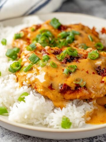 Chicken Diablo with creamy sauce, topped with chopped green onions, served over a bed of white rice.