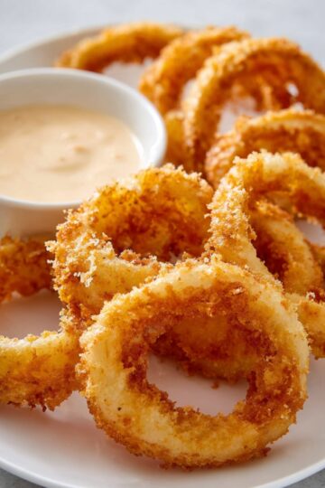 Easy Onion Rings Recipe | 8 Steps to Crispy Perfection 19 Onion Rings Recipe Golden crispy onion rings served on a white plate with creamy dipping sauce in a small bowl, crunchy texture visible, restaurant-style plating, bright natural light, high-resolution food photography.