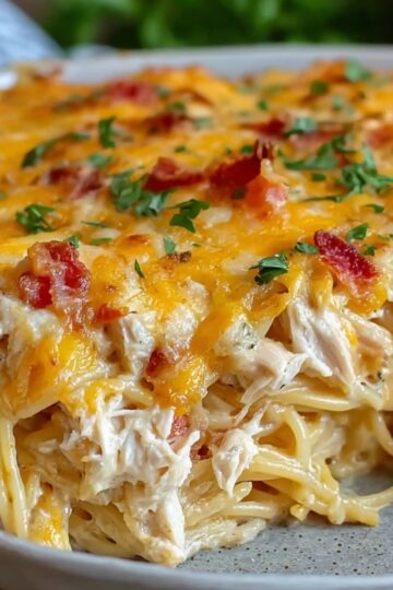 chicken spaghetti casserole A beautifully plated serving of chicken spaghetti casserole, with crispy golden cheese and some garnishing.