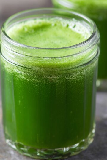 6-Ingredient Green Juice Recipe (Ready in 15 Minutes!) 10 green juice recipe Glass jar filled with bright green juice, smooth texture with light foam on top, blurred background with another jar behind, close-up composition, natural soft lighting, healthy detox drink, professional food photography, high realism, editorial style