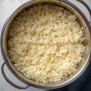 Italian Penicillin Soup Recipe 15 Top-down view of freshly cooked rice in a stainless steel pot, fluffy rice grains ready to be added to soup