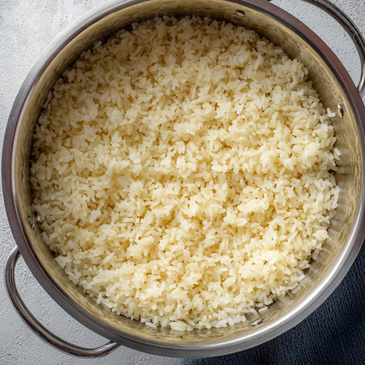 Italian Penicillin Soup Recipe 11 Top-down view of freshly cooked rice in a stainless steel pot, fluffy rice grains ready to be added to soup