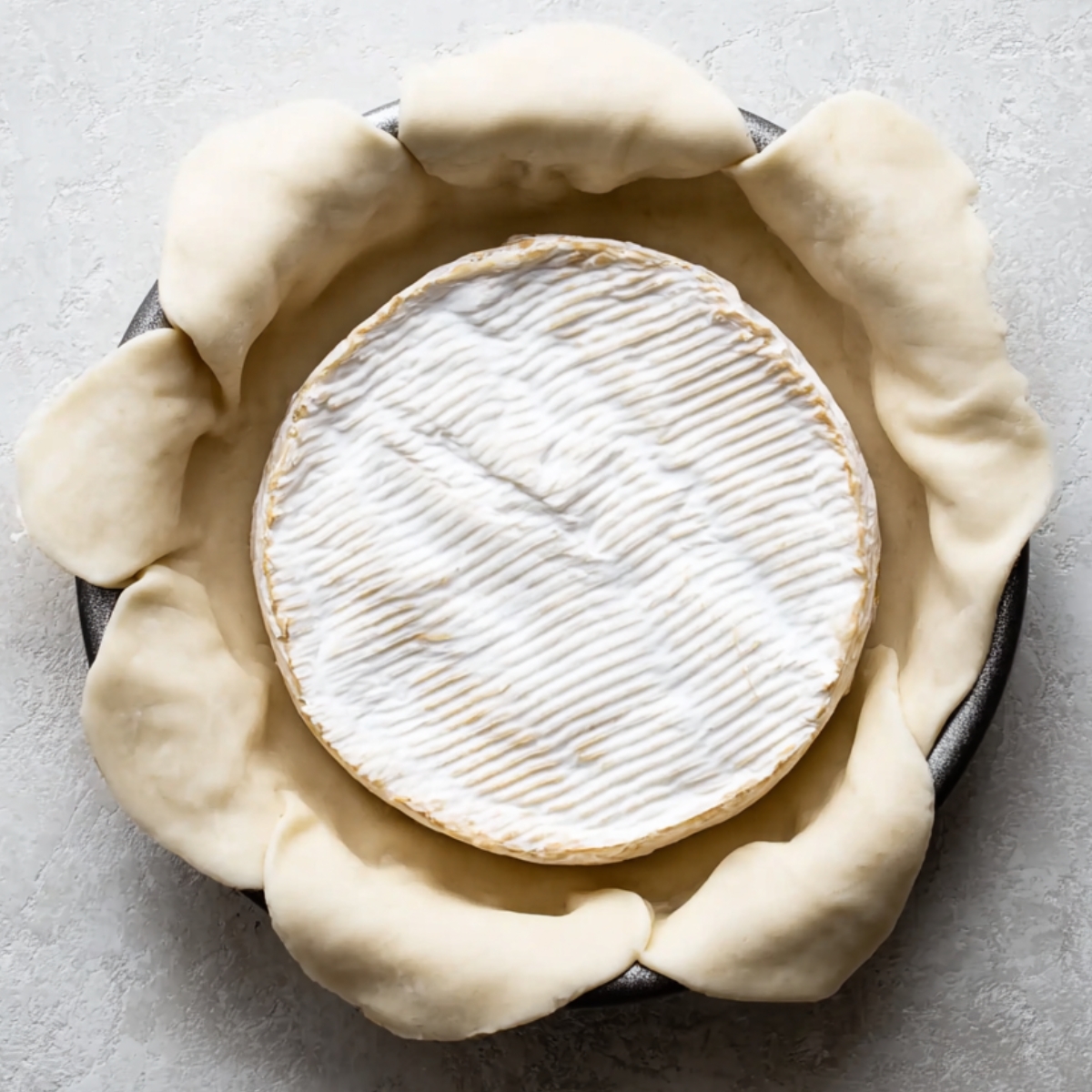 Easy Baked Brie in Puff Pastry Recipe 10 Wheel of brie cheese placed in puff pastry before baking in a round pan