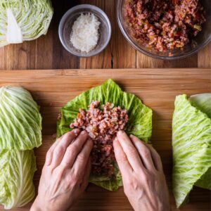 Cabbage Rolls Recipe 17 Hands wrapping seasoned ground meat and rice inside a cabbage leaf, preparing stuffed cabbage rolls