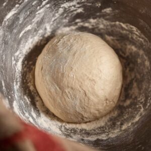 Chocolate Croissants Recipe 15 Smooth croissant dough ball resting in a mixing bowl, lightly floured sides, bread dough fermentation stage, soft natural lighting, close-up food photography, realistic texture