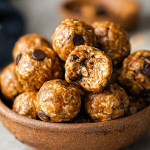 Energy Ball Recipe | No-Bake Snack Ready in 10 Minutes 16 No-bake peanut butter energy balls piled in a rustic ceramic bowl with oats and chocolate chips, healthy homemade snack
