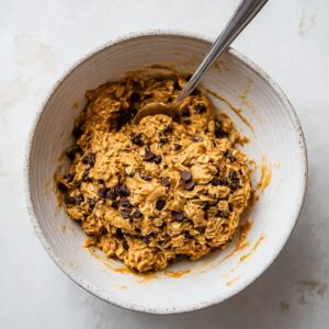 Energy Ball Recipe | No-Bake Snack Ready in 10 Minutes 14 Peanut butter oat mixture with chocolate chips in a white bowl, preparing no-bake energy balls, healthy snack prep