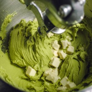 Easy Matcha Cookies Recipe 14 Macro food photography of matcha cookie dough mixing in a stand mixer bowl, paddle attachment blending green dough with white chocolate pieces, smooth creamy texture, bright kitchen lighting, high detail