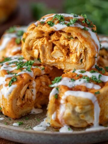 Buffalo Chicken Roll Ups drizzled with ranch and garnished with parsley.