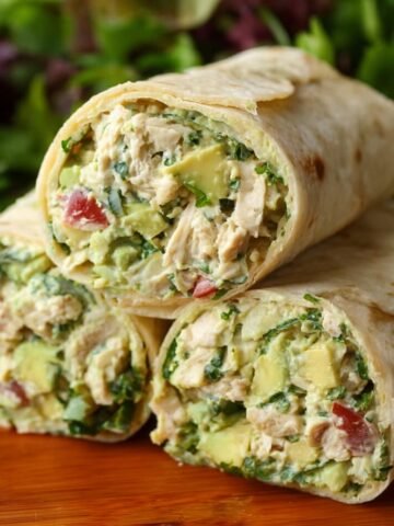 A close-up of chicken and avocado wraps, sliced to show the creamy filling made of shredded chicken, avocado, and fresh vegetables, wrapped in soft tortillas.